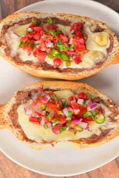 Toasted bolillo bread or Mexican molletes topped with beans, melted cheese, tomatoes, onions and jalape&ntilde;os