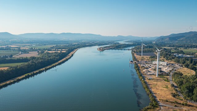 Le Pouzin, France - 12 July 2026: Aerial view of the Rhone River featuring wind turbines and renewable energy infrastructure set against a scenic valley landscape under a clear sky.