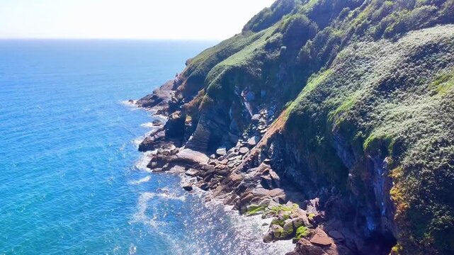 Aerial view of the rugged cliffs and blue sea at Lantic Bay, a National Trust site, near the coastal village of Polruan, United Kingdom.