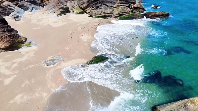 Aerial view of Lantic Bay beach with turquoise water, sandy shore, and rocky cliffs in Polruan, United Kingdom.