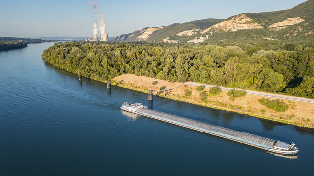 Saulce-sur-Rhone, France - 12 July 2026: Aerial view of a cargo barge on the Rhone River with the Cruas Nuclear Power Plant and cooling towers in the background.