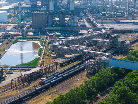 Aerial view of Humber Refinery chemical plant with industrial piping, storage tanks, and a freight train on tracks in South Killingholme, England, United Kingdom.