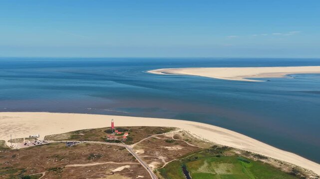 Aerial view of the iconic red Texel Lighthouse surrounded by sandy dunes and the North Sea coastline in De Cocksdorp, Noord-Holland, Netherlands.