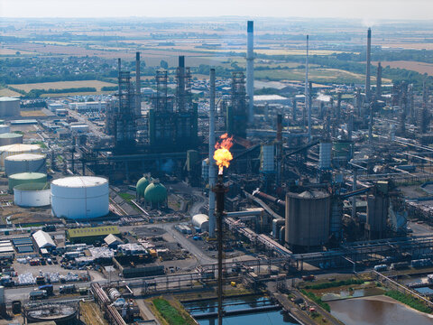 Aerial view of Humber Refinery, a large industrial chemical plant with storage tanks, complex piping, and a burning flare stack in South Killingholme, England, United Kingdom.