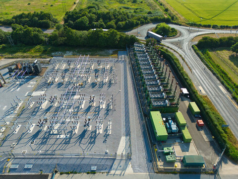 Aerial view of an electrical substation and containerized industrial generator compressor units located near a road and roundabout in Immingham, England, United Kingdom.