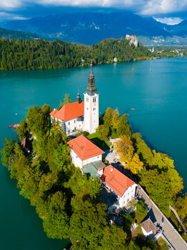 Aerial view of the Pilgrimage Church of the Assumption of Maria on the island in Lake Bled surrounded by lush trees and turquoise water in Bled, Radovljica, Slovenia.
