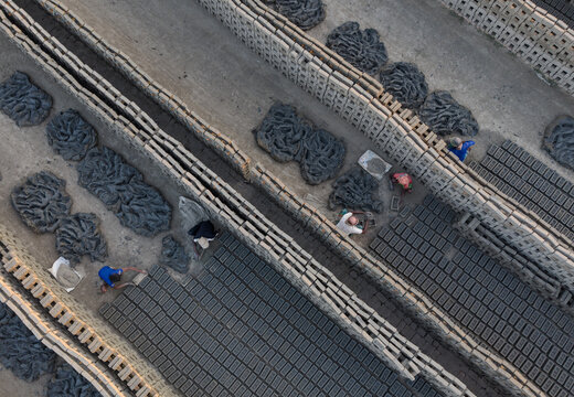 Chattogram, Bangladesh - 07 February 2026: View of workers arranging rows of clay bricks in a traditional brickyard.