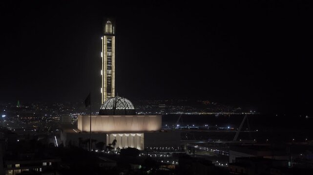 Aerial view of the illuminated Great Mosque of Algiers with city lights glowing in the background at night in Algeria.