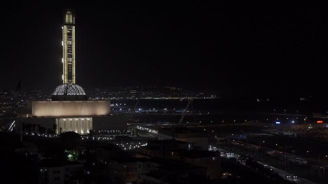 Aerial view of the illuminated Great Mosque of Algiers at night with its prominent minaret and surrounding urban lights in Algeria.