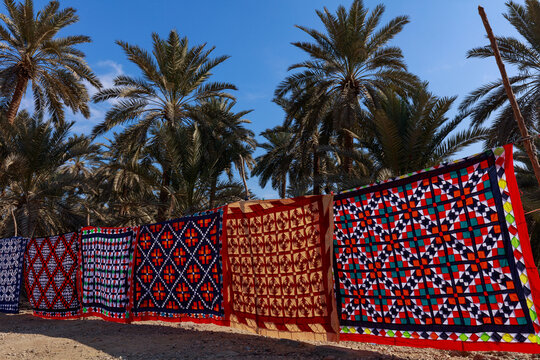 View of traditional colorful Ralli quilts hanging on a line in a palm grove in Nagarparkar, Sindh, Pakistan.