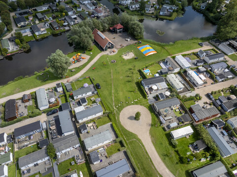 Aerial view of De Holle Poarte holiday park featuring numerous vacation bungalows, canals, green lawns, and recreational facilities in Makkum, Friesland, Netherlands.