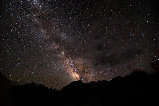 View of the Milky Way galaxy stretching across the night sky above the dark silhouettes of the Karakoram mountains near Askole, Gilgit Baltistan, Pakistan.