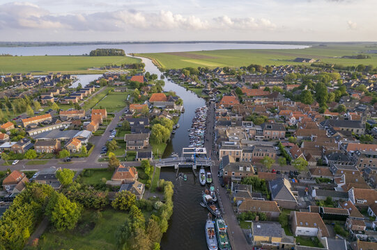 Aerial view of the historic village of Woudsend with its canal, moored boats, drawbridge, and surrounding green fields in Woudsend, Friesland, Netherlands.