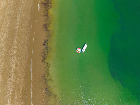 Aerial view of a small boat and a colorful floating ring in the turquoise waters off the coast of Ayangue, Santa Elena, Ecuador.