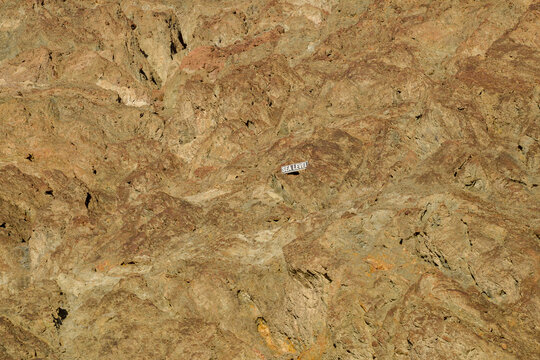 View of the rugged rocky terrain of Death Valley National Park's backcountry featuring a sea level sign mounted on the cliff face in Death Valley, California, United States.