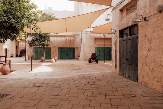 Dubai, United Arab Emirates - 20 April 2024: View of the historic Al Fahidi neighbourhood with traditional stone walls, wooden doors, and sun shades in a quiet courtyard.