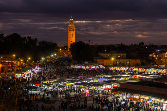 Marrakesh, Marrakesh-Safi, Morocco - 12 November 2025: View of the bustling Jemaa el-Fnaa square at night, with the illuminated Koutoubia Mosque minaret towering over crowded market stalls.