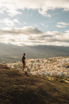 Chefchaouen, Tangier-Tetouan-Al Hoceima, Morocco - 14 November 2025: View of a man on a hillside overlooking the historic blue city of Chefchaouen with dense buildings.