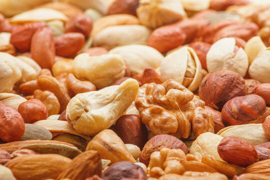 Variety of nuts and seeds closeup with selective focus - peeled walnut, hazelnuts, peeled peanut, pine nut kernels, almond seeds, cashew seeds, pistachio nuts in the shell, pumpkin seeds