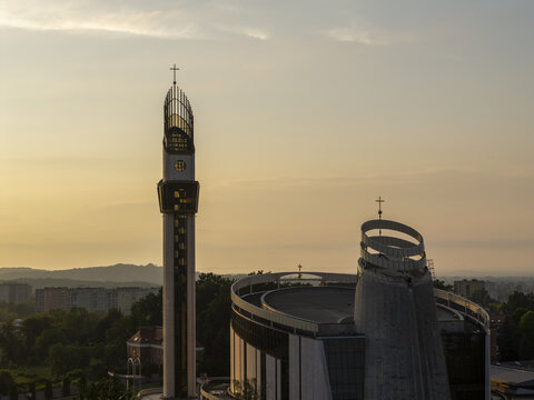Aerial view of the Sanctuary of Divine Mercy featuring its modern bell tower and circular architecture during golden hour in Krakow, Lesser Poland Voivode, Poland.