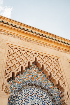 Rabat, Morocco - 14 November 2025: View of intricate zellij tilework and carved stucco archway of a historic building under a clear sky.