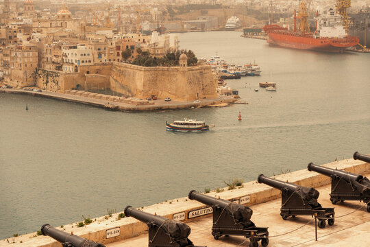 Valletta, Malta - 14 July 2022: View of the historic Saluting Battery with its cannons overlooking the Grand Harbour and the cityscape of Valletta, Malta.