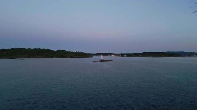 Aerial view of a navigation buoy in the foreground and a distant lighthouse on a small island in the calm waters of the Oslofjord Oslo, Oslo, Norway.