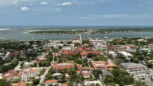 Aerial view of the historic district of St. Augustine, featuring the iconic architecture of Flagler College, lush trees, and the coastal waterfront in St. Augustine, Florida, United States.