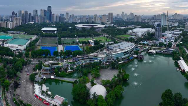Aerial view of Danau Promenade Senayan Park with its modern shopping complex, fountains, and lush greenery, set against the Jakarta skyline in Tanah Abang, Jakarta, Indonesia.