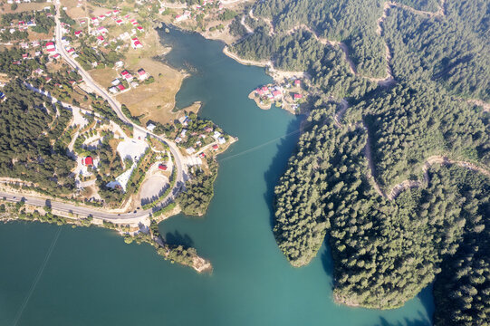 Andirin, Kahramanmaras, Turkiye - 20 June 2026: Aerial view of Kesik Baraj reservoir surrounded by pine forests, winding roads, and small settlements with red-roofed houses.