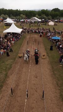 Loveland, Colorado, United States - 09 June 2024: Aerial view of a jousting match at the Colorado Medieval Festival with knights on horseback and spectators in white tents.
