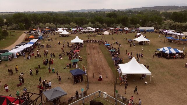 Loveland, United States - 09 June 2024: Aerial view of the Colorado Medieval Festival featuring numerous white tents, a jousting track, and visitors in period costumes.