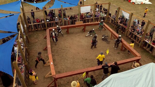 Loveland, Colorado, United States - 09 June 2024: Aerial view of knights in armor fighting in the arena at the Colorado Medieval Festival, surrounded by spectators and blue shade sails.