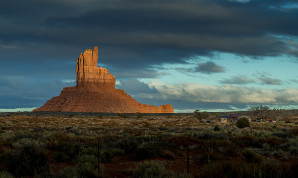 View of the iconic red rock formations at Monument Valley Tribal Park under dramatic storm clouds during golden hour in Oljato-Monument Valley, Utah, United States.