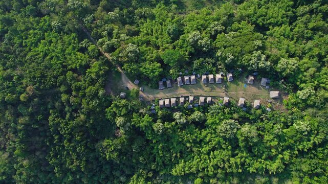 Aerial view of Kampung Adat Belaraghi with traditional houses nestled within dense tropical forest and lush greenery in Kecamatan Aimere, Nusa Tenggara Timur, Indonesia.