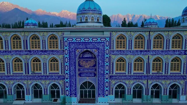 Aerial view of the Grand mosque of Skardu with intricate blue tile work and domes set against mountain peaks in Skardu, Gilgit Baltistan, Pakistan.