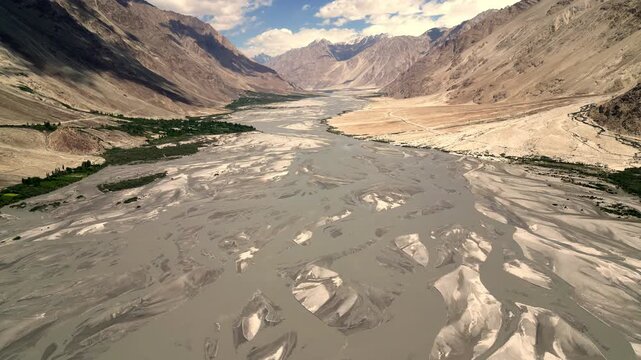 Aerial view of Charasa Gonpa nestled within the vast, braided river landscape of the Ladakh valley, featuring rugged mountain slopes and clear skies in Charasa, Ladakh, India.