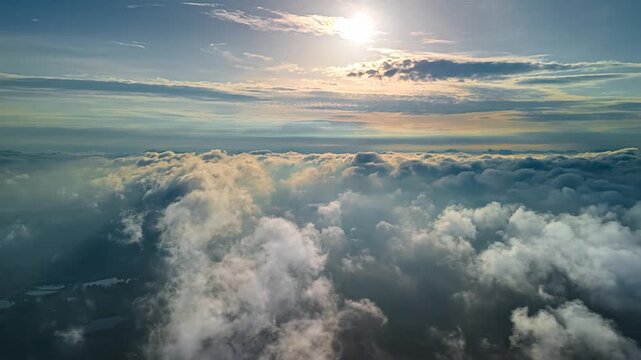 Aerial view of bright sun shining over a vast layer of fluffy clouds covering the landscape in Latvia.
