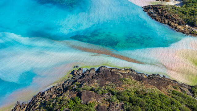 Aerial view of Chance Bay featuring turquoise waters, white sand beaches, and rocky coastline with lush vegetation in Whitsundays, Queensland, Australia.
