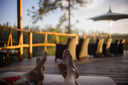 Two people's feet relaxing on a chair at sunset in Eastern Belize, Central America