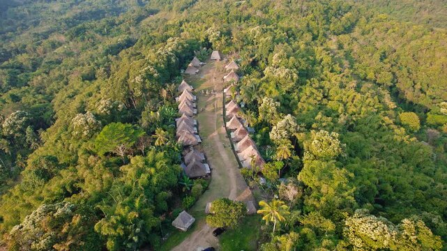 Aerial view of the traditional village of Kampung Adat Belaraghi nestled within a lush tropical forest in Kecamatan Aimere, Nusa Tenggara Timur, Indonesia.