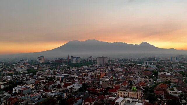 Aerial view of Malang city at sunset with Gunung Butak, Gunung Kawi, and Gunung Panderman as one called Barisan Putri Tidur in the background, Malang, East Java, Indonesia.