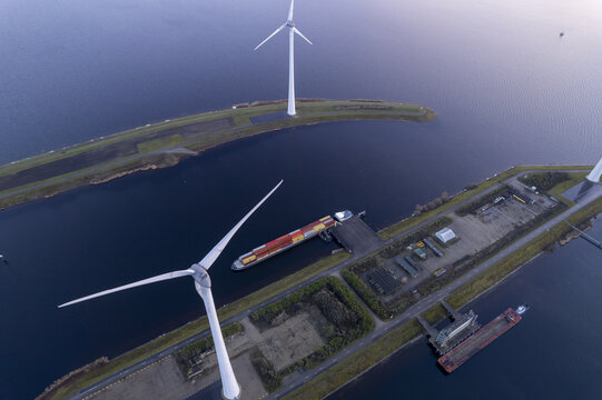 Aerial view of the Krammer locks featuring wind turbines and a cargo ship navigating the canal in Bruinisse, Zeeland, Netherlands.