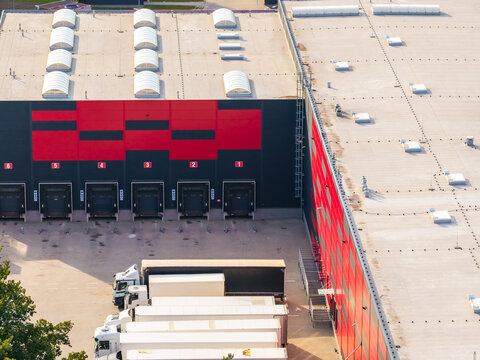 Aerial view of a modern logistics center with loading docks, numbered bays, and parked semi-trucks in Kowale, Pomeranian Voivodeship, Poland.