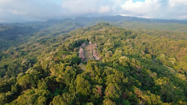 Aerial view of Kampung Adat Belaraghi traditional village surrounded by lush tropical forest and mountains in Kecamatan Aimere, Nusa Tenggara Timur, Indonesia.