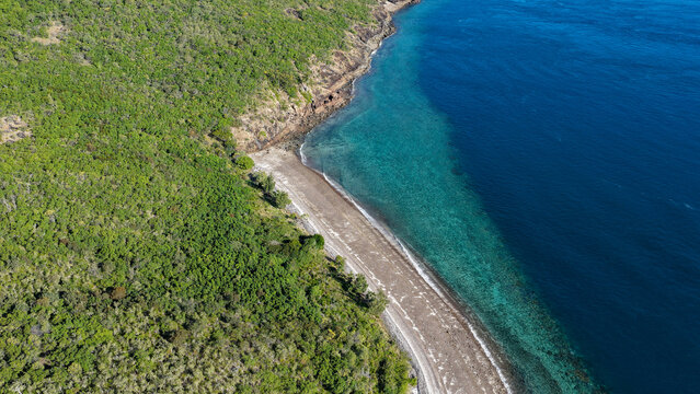 Aerial view of Haslewood Island featuring a pristine sandy beach bordered by lush green vegetation and clear turquoise waters in Whitsundays, Queensland, Australia.