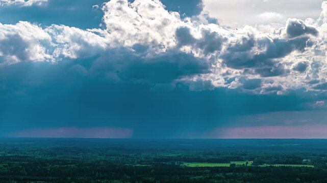 Aerial view of dramatic sunbeams breaking through heavy clouds over the vast forested landscape of Latvia.