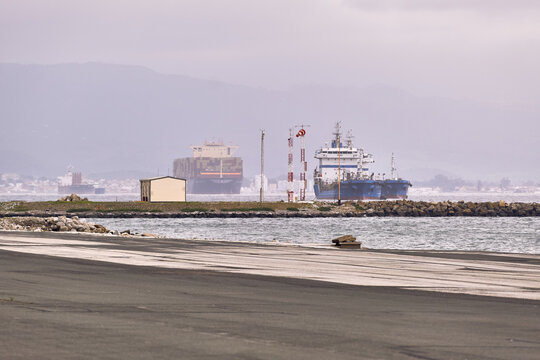 Gibraltar, Gibraltar - 01 March 2026: View of the tarmac of Gibraltar International Airport with cargo ships and a tanker anchored in the bay under a cloudy sky.