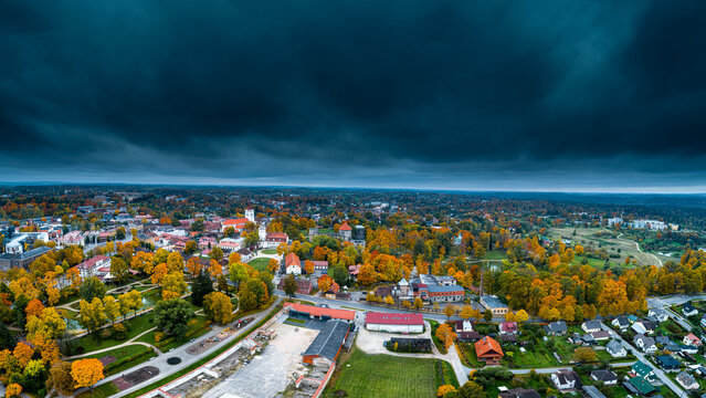 Aerial view of Cesis Castle ruins surrounded by vibrant autumn foliage and historic architecture under a dramatic dark sky in Cesis, Cesis Municipality, Latvia.