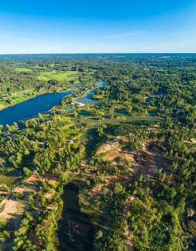 Aerial view of a lush landscape with winding lakes, dense forests, and patches of cleared land in Latvia.